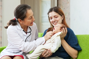 mother holds her baby up for an older female physician to exam