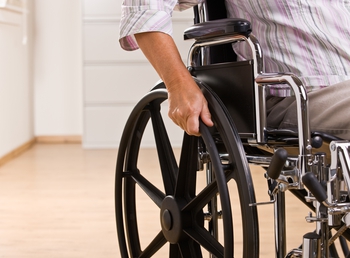 patient in a wheelchair cropped to focus on their hand and wheel